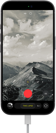 iPhone 18 Pro, front exterior, displaying a mountainous landscape, with the camera mode overlay in Time-Lapse mode, with power cable attached to charging port